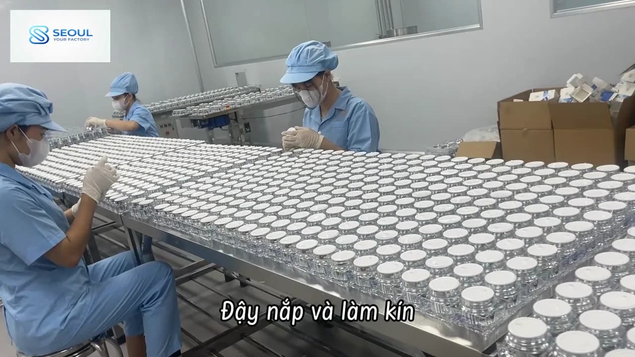 Công nhân đậy nắp hũ kem trên bàn dài trong khu đóng gói