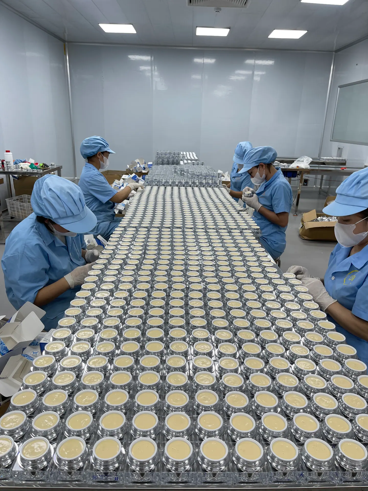 Công nhân đóng hộp hũ kem thành phẩm trên bàn hoàn thiện