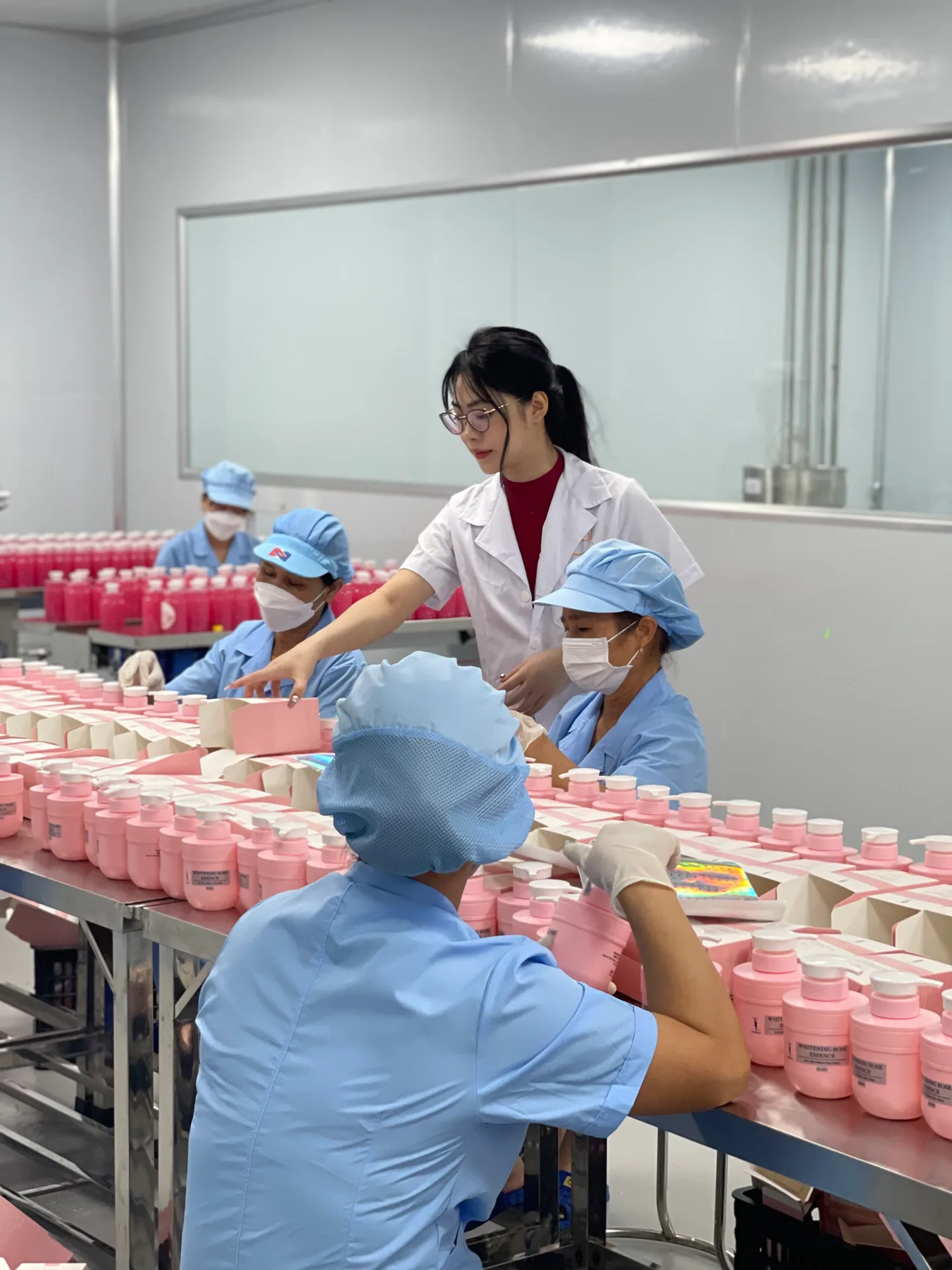Công nhân đóng gói chai và hũ thành phẩm trên bàn dây chuyền