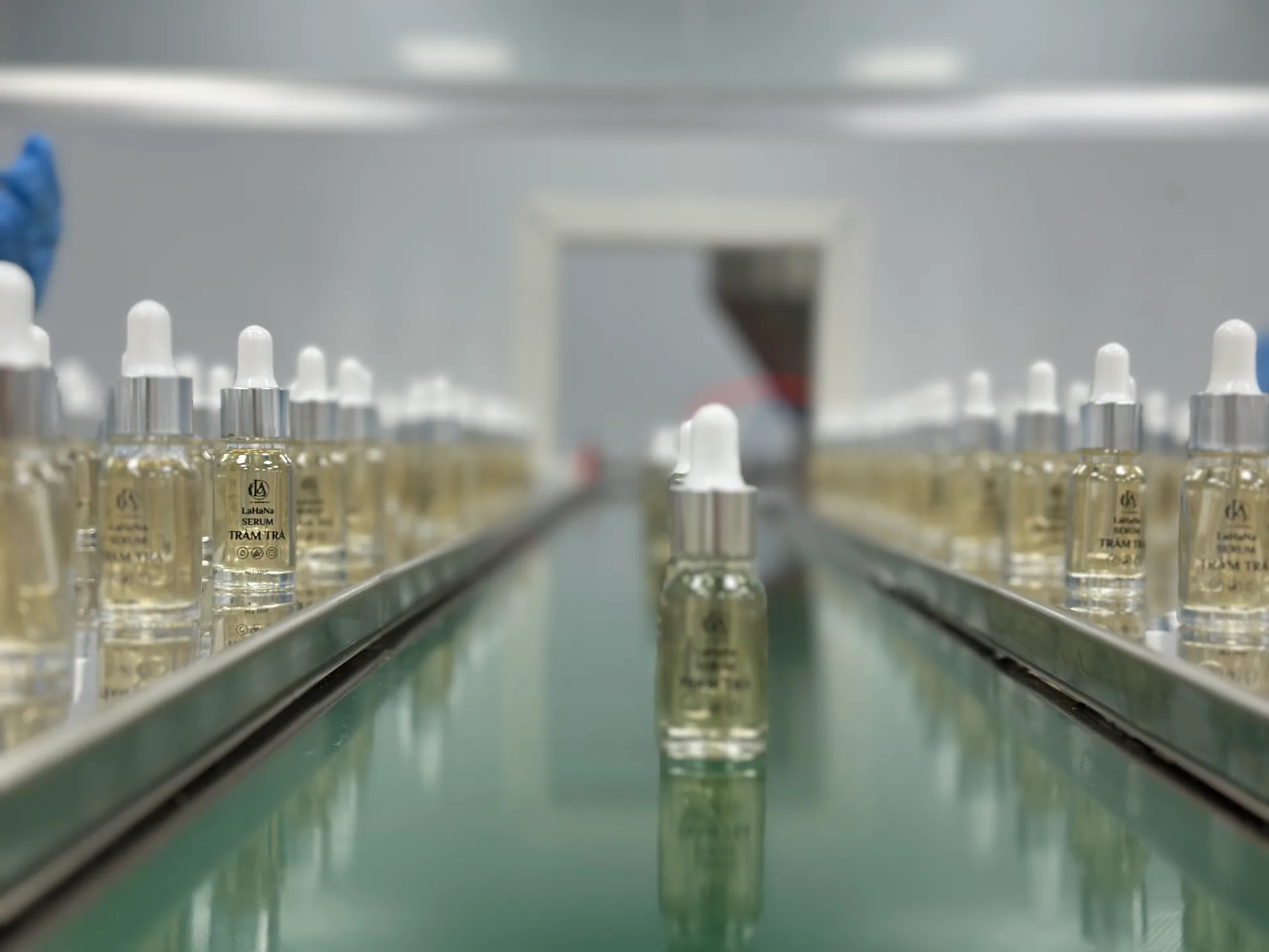 Hai hàng chai serum trên băng chuyền hoàn thiện của nhà máy