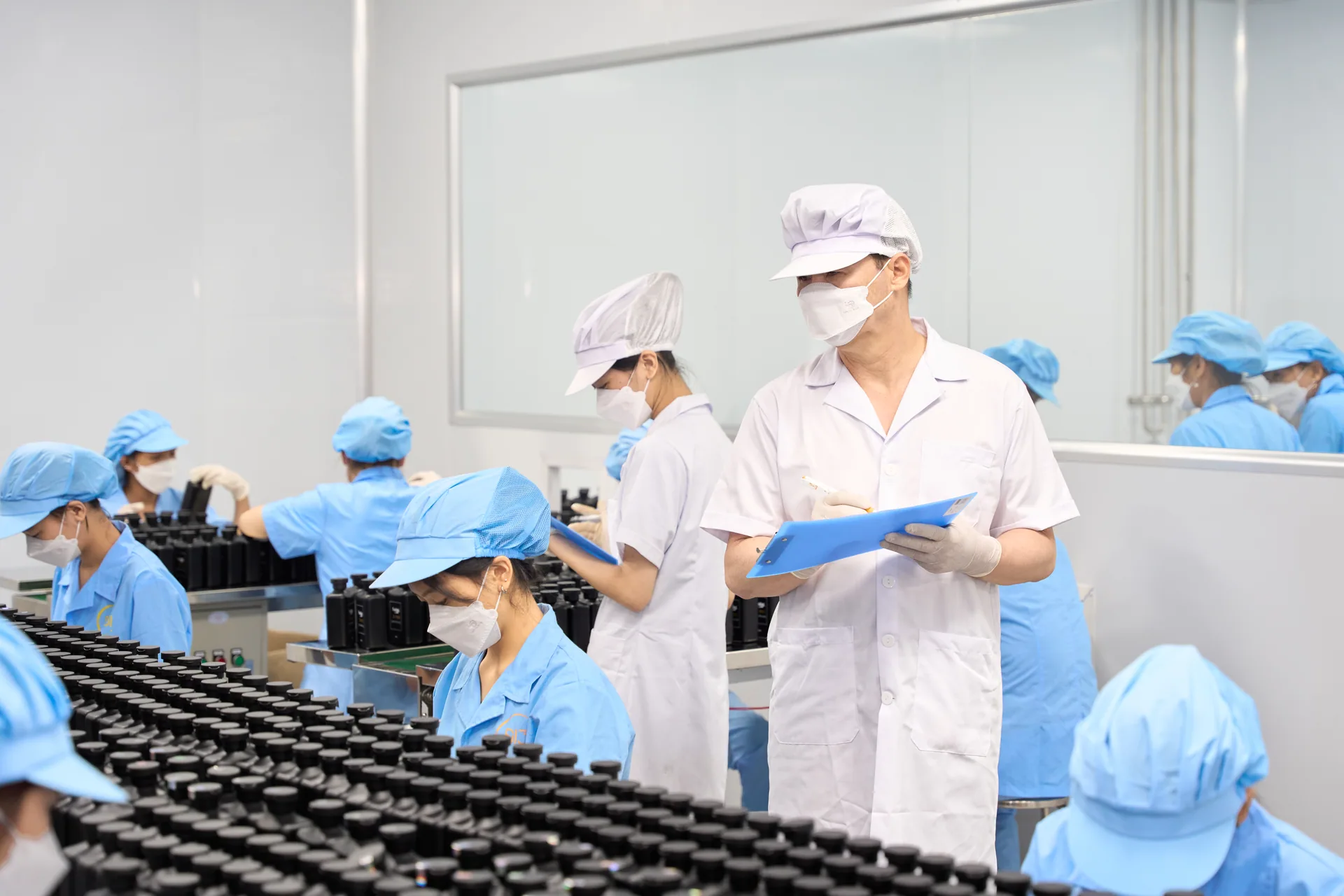 Giám sát cầm bảng kẹp hồ sơ bên dây chuyền chai thành phẩm